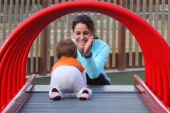 Kelsey Newman encourages Henry "Huck" Hughes crawl through a roller tunnel at the Malone Park Playground in New Berlin on Feb. 22 as warm, unseasonable weather brought families out of their homes for an afternoon at the park.