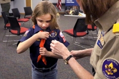 Lucia Cronin (right) helps Lucy Riechert  put on the slide to her  Tiger cub neckerchief  before the start of the first meeting of Den 7, Pack 505, one of two new girl Cub Scout dens to form in the area. Den 7 gathered for the first time in a meeting room at the Greendale Library on Feb. 8.